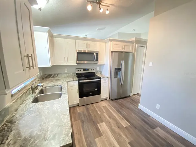 a kitchen with kitchen island a counter top space a sink and stainless steel appliances