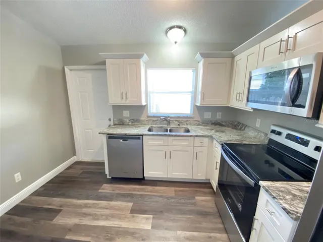 a kitchen with granite countertop a stove top oven sink and cabinets