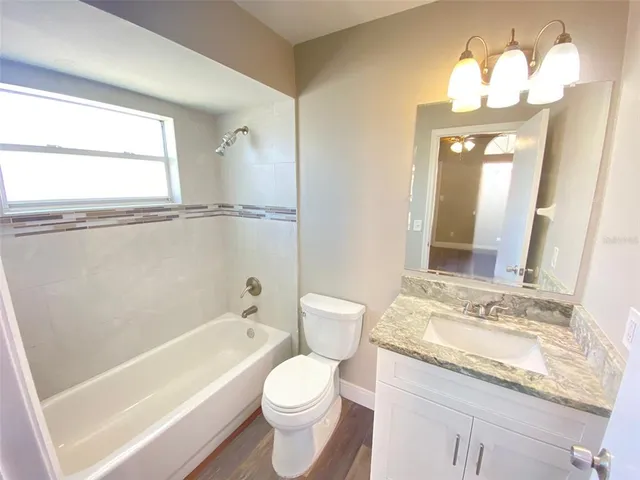 a bathroom with a granite countertop sink a toilet and bathtub