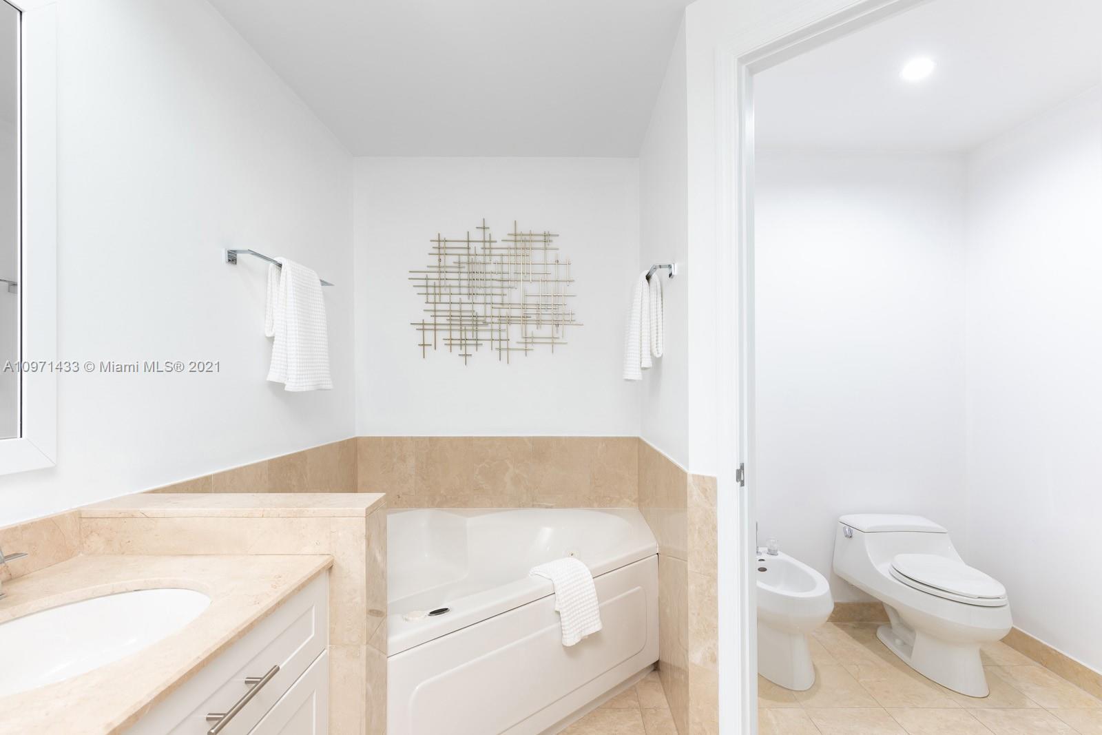 848 Brickell Key Drive, Unit 904 Miami, FL 33131 - Photo 15 of 31 a bathroom with a granite countertop sink a toilet and shower