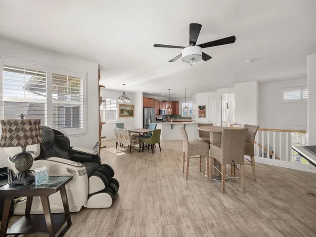 a living room with lots of furniture wooden floor and a large window