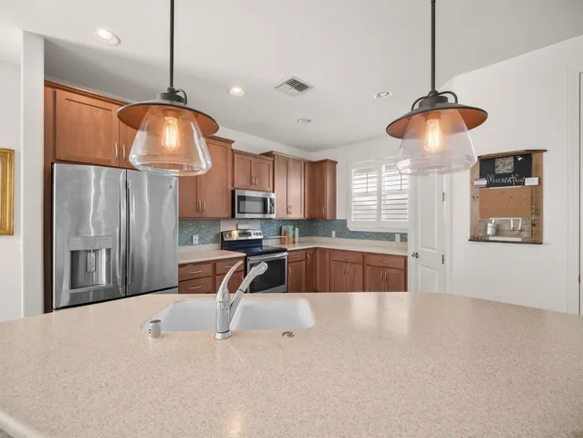 a kitchen with stainless steel appliances granite countertop a sink a refrigerator and a stove
