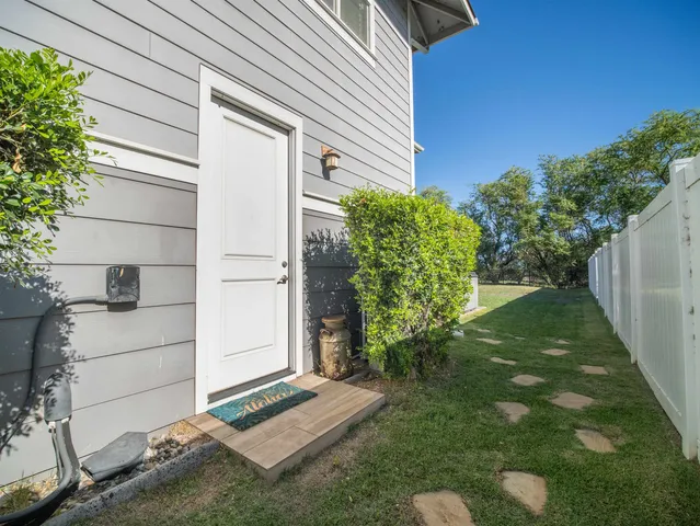 a backyard of a house with large trees and plants