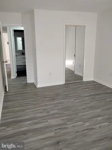 a view of an empty room with wooden floor and a bathroom