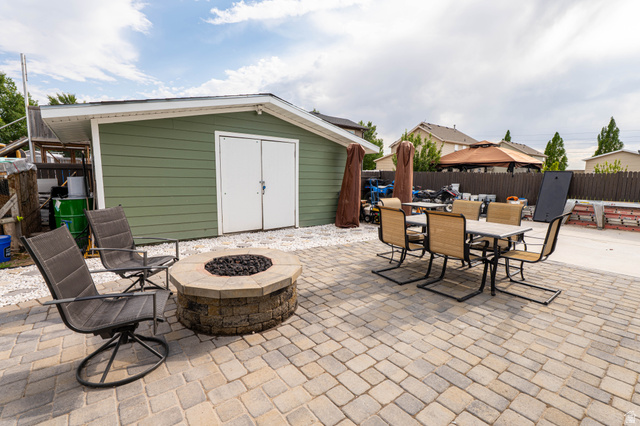 1443 West 250 North Springville, UT 84663 - Photo 21 of 23 Expansive paver patio featuring a built-in stone fire pit, a dedicated concrete pad, and a storage shed with double doors