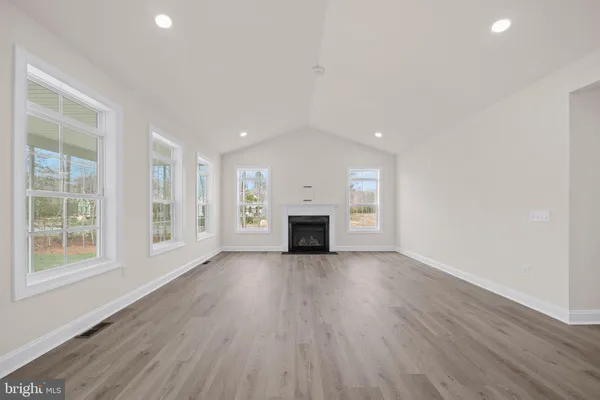 an empty room with wooden floor fireplace and windows
