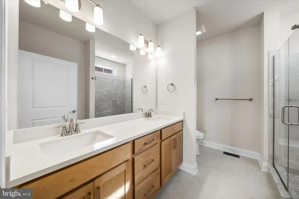 a bathroom with a double vanity sink mirror and shower