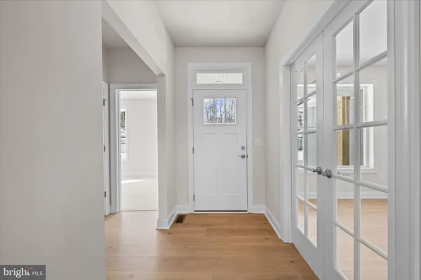 a view of a hallway with wooden floor and a bathroom