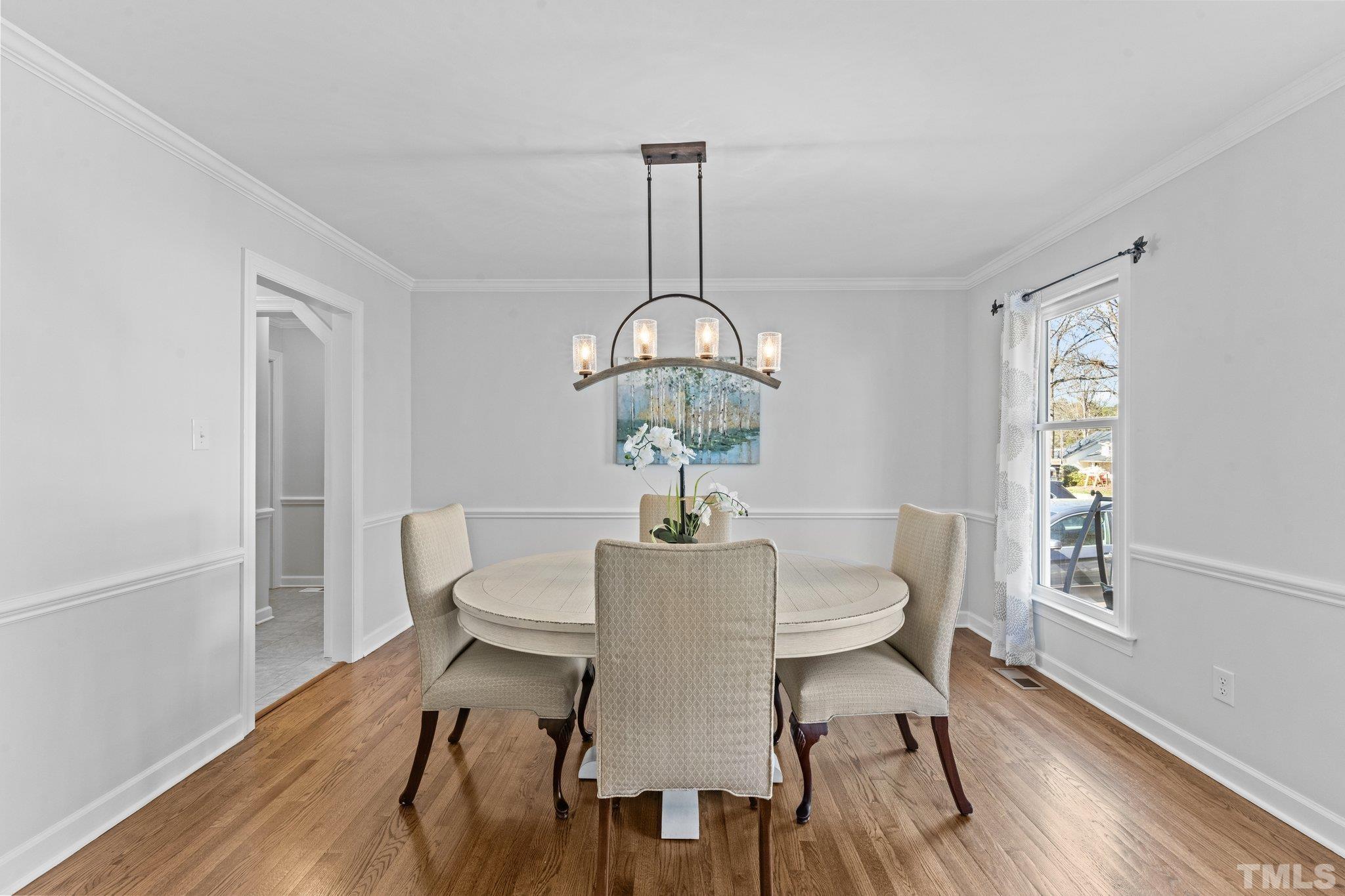 8325 Apple Orchard Way Raleigh, NC 27615 - Photo 9 of 54 a dining room with furniture a chandelier and wooden floor