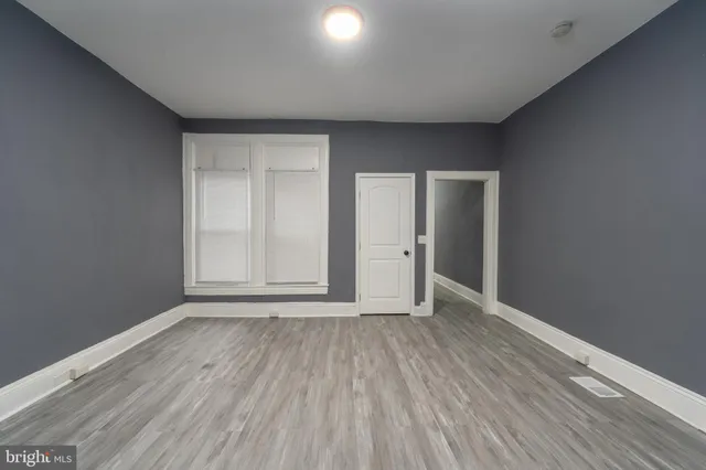 a view of an empty room with wooden floor and closet