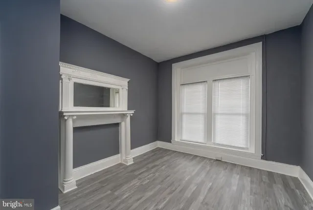 a view of an empty room with a fireplace and wooden floor