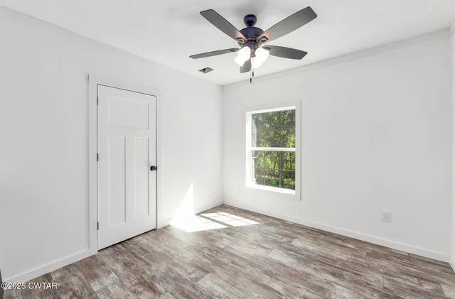 an empty room with a window and a fan
