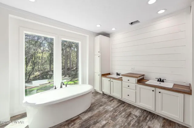 a spacious bathroom with a double vanity sink a mirror and a bathtub