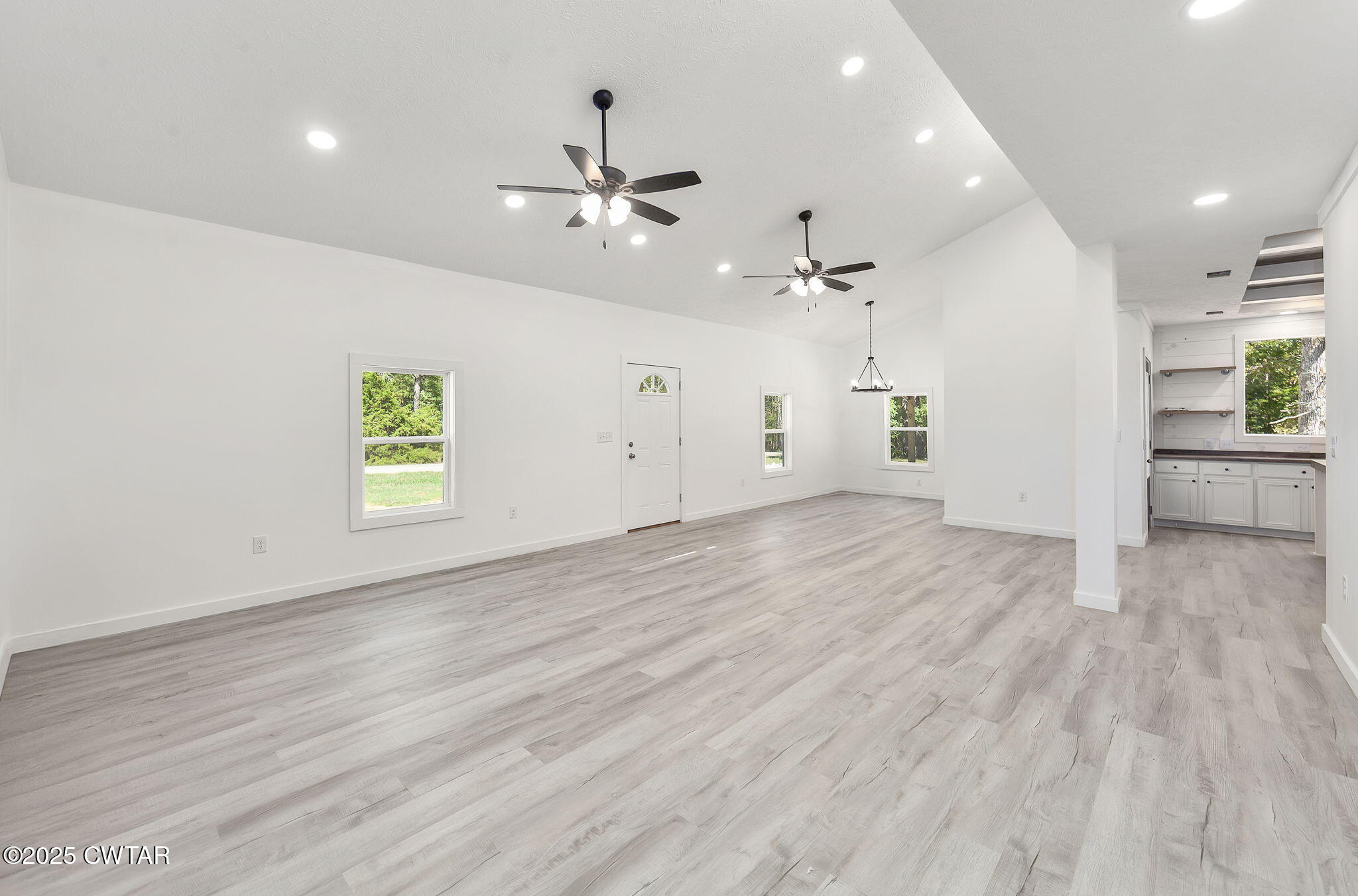 2885 Old Friendship Road Finger, TN 38334 - Photo 5 of 50 an empty room with wooden floor a ceiling fan and windows