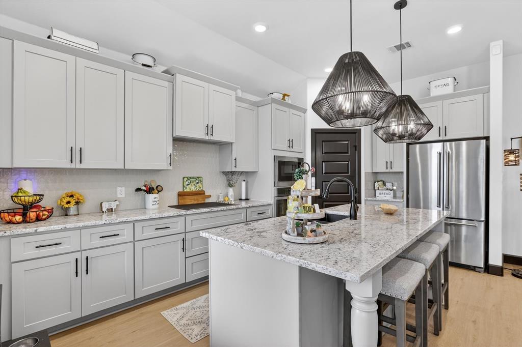 1740 Reverie Road Burleson, TX 76028 - Photo 21 of 37 a kitchen with stainless steel appliances granite countertop a sink a stove and chairs with white cabinets