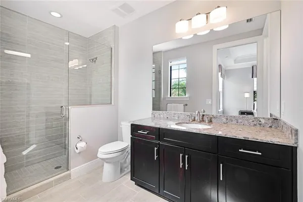 a bathroom with a granite countertop sink toilet a large mirror a shower and a mirror