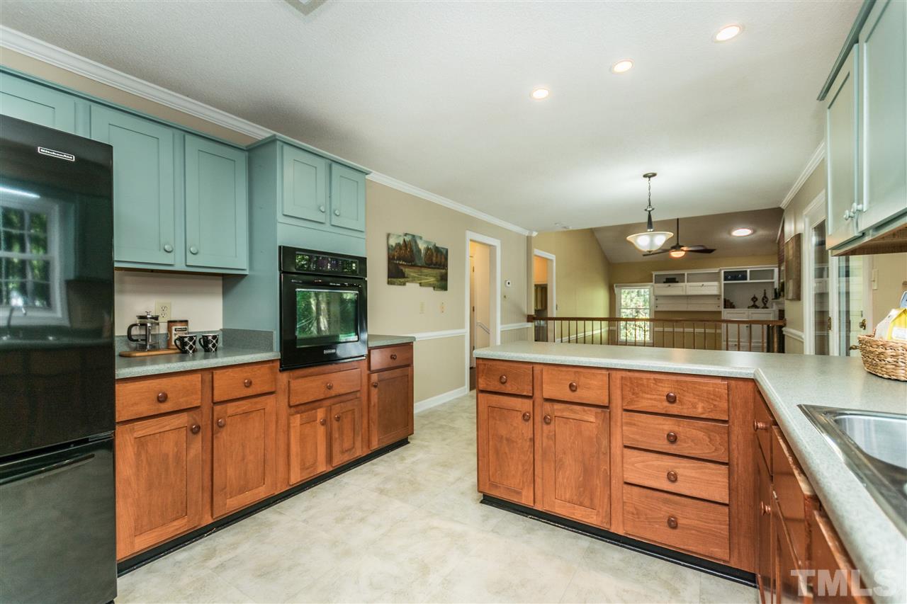 5606 Red Coach Road Durham, NC 27712 - Photo 7 of 25 a kitchen with granite countertop wooden cabinets and white appliances