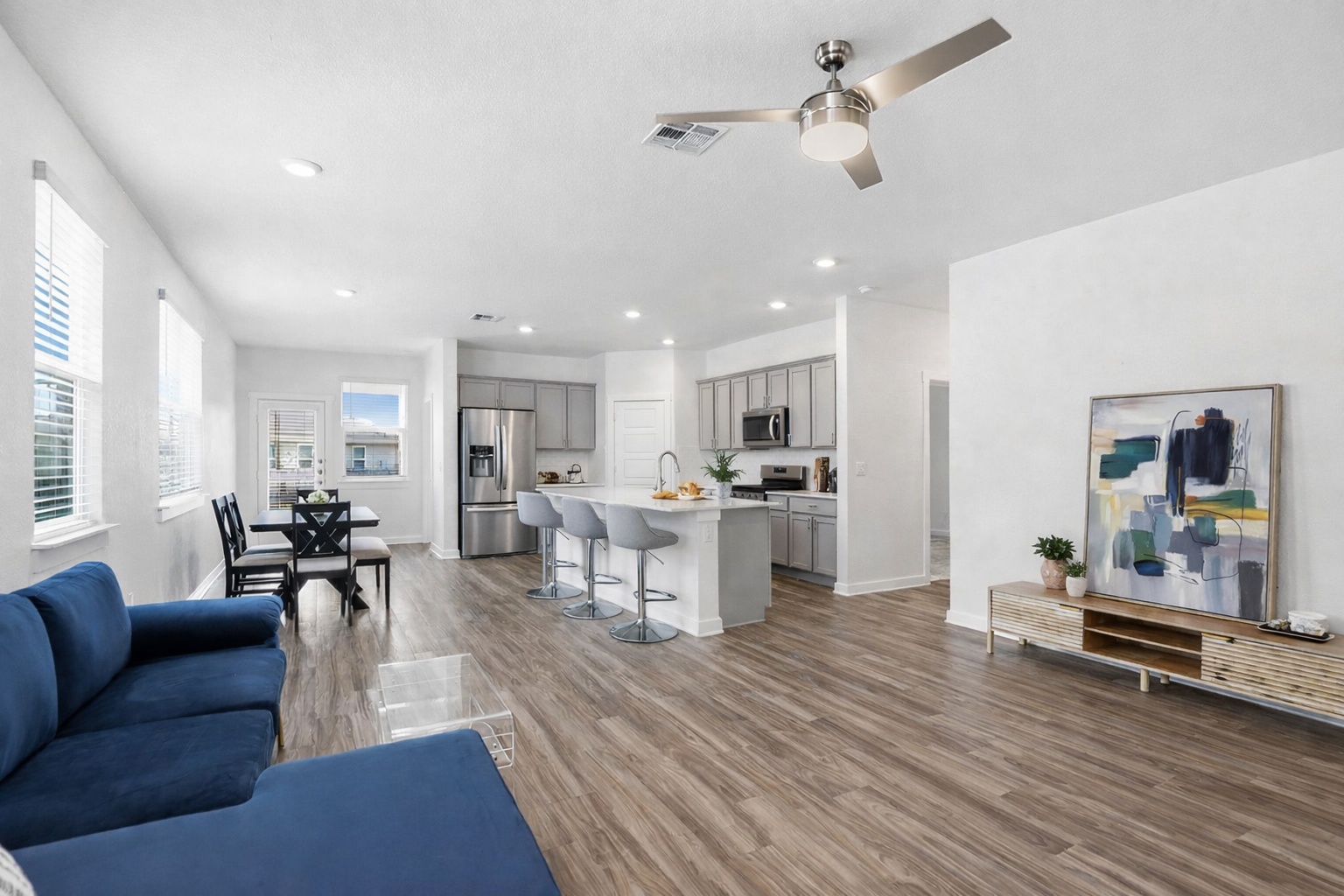 a living room with furniture kitchen view and a wooden floor