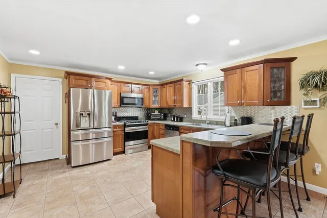 a kitchen with stainless steel appliances granite countertop a stove a refrigerator a sink a dining table and chairs