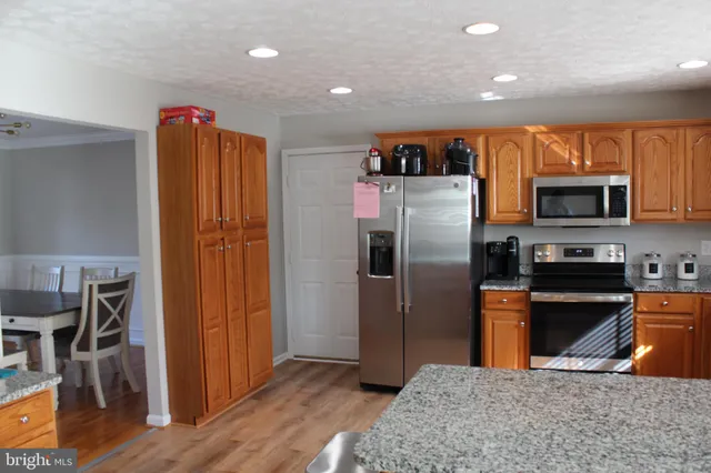 a kitchen with stainless steel appliances granite countertop a refrigerator a stove top oven a sink and dishwasher