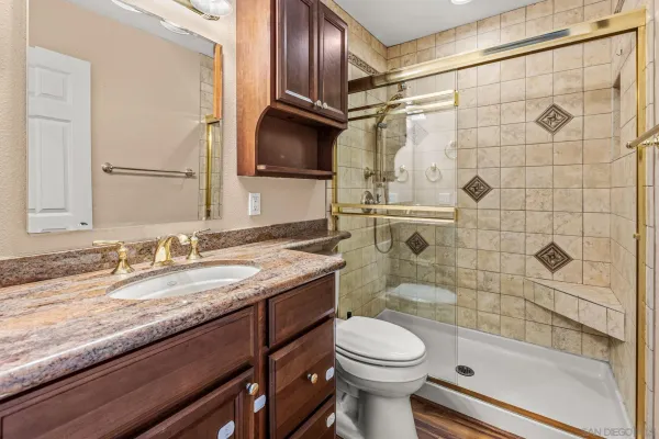 a bathroom with a granite countertop sink toilet and shower
