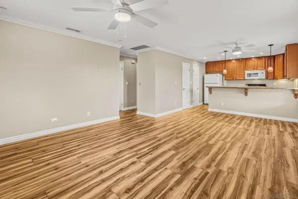 a view of a room with wooden floor and a ceiling fan