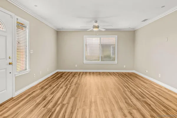 a view of an empty room with wooden floor and a window