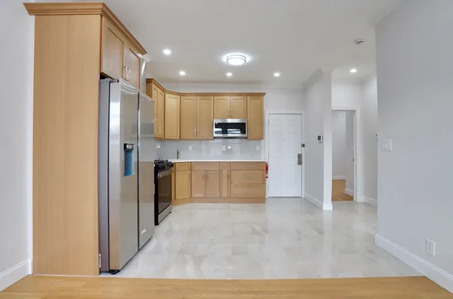 a large kitchen with stainless steel appliances granite countertop a granite counter top and a refrigerator