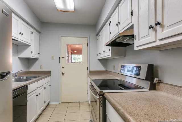 a kitchen with granite countertop a sink stove and refrigerator