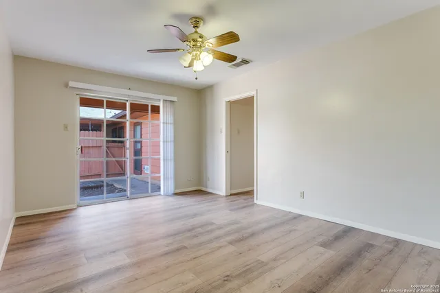 an empty room with a chandelier fan and windows