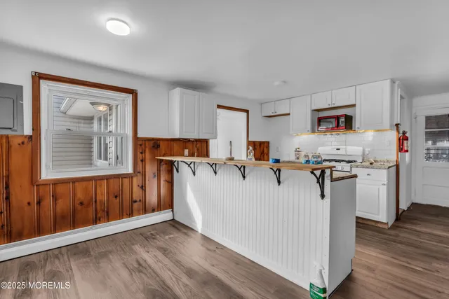 a living room with stainless steel appliances granite countertop a refrigerator a stove top oven a sink dishwasher and wooden cabinets with wooden floor