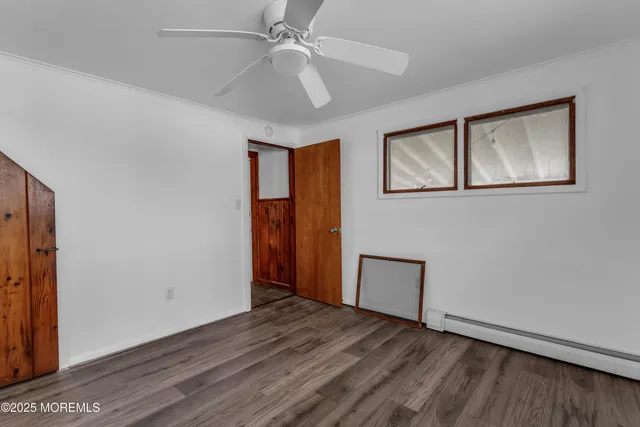 a view of an empty room with wooden floor and a ceiling fan