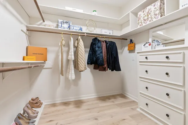a view of walk in closet with clothes and shoes