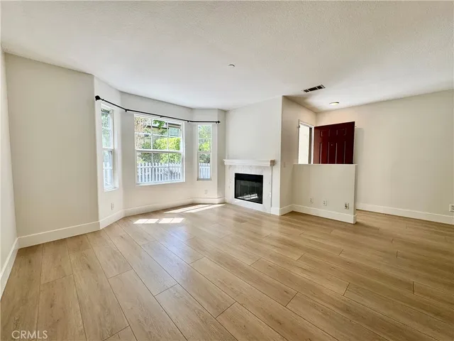 a view of empty room with wooden floor and fireplace
