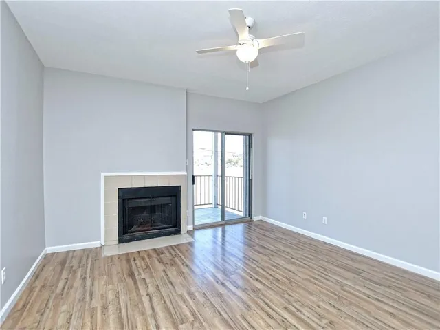 an empty room with wooden floor a fireplace a ceiling fan and wooden floor