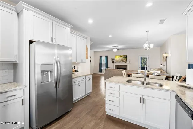 a kitchen with stainless steel appliances kitchen island a refrigerator sink and white cabinets
