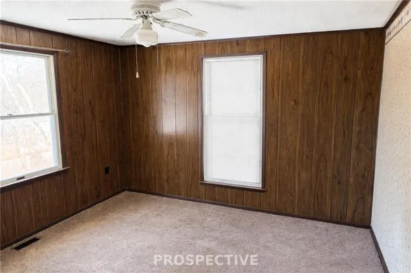 an empty room with windows and fan
