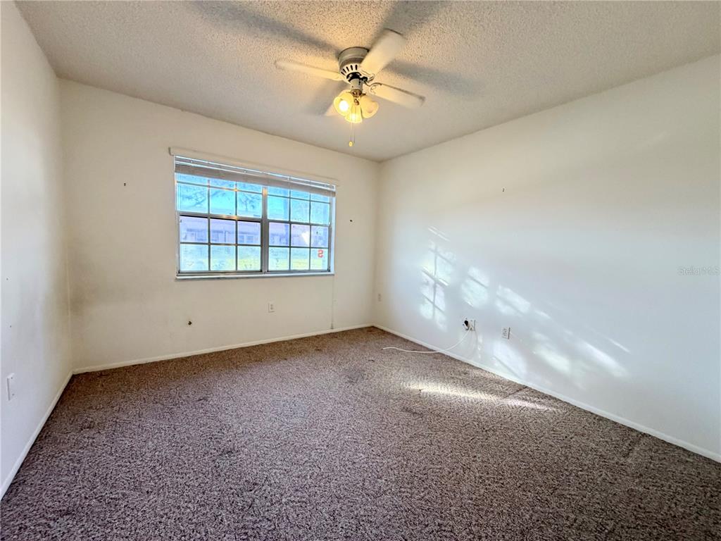 11210 Dollar Lake Drive, Unit 2 Port Richey, FL 34668 - Photo 11 of 15 an empty room with windows and ceiling fan