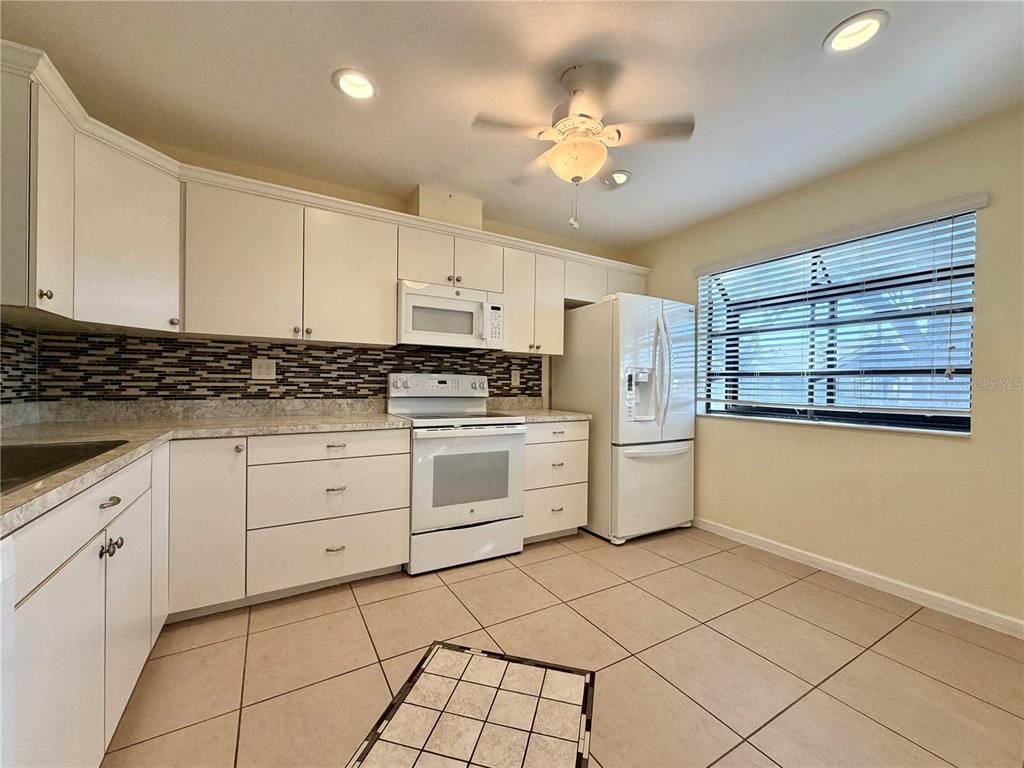11210 Dollar Lake Drive, Unit 2 Port Richey, FL 34668 - Photo 4 of 15 a kitchen with white cabinets and white appliances