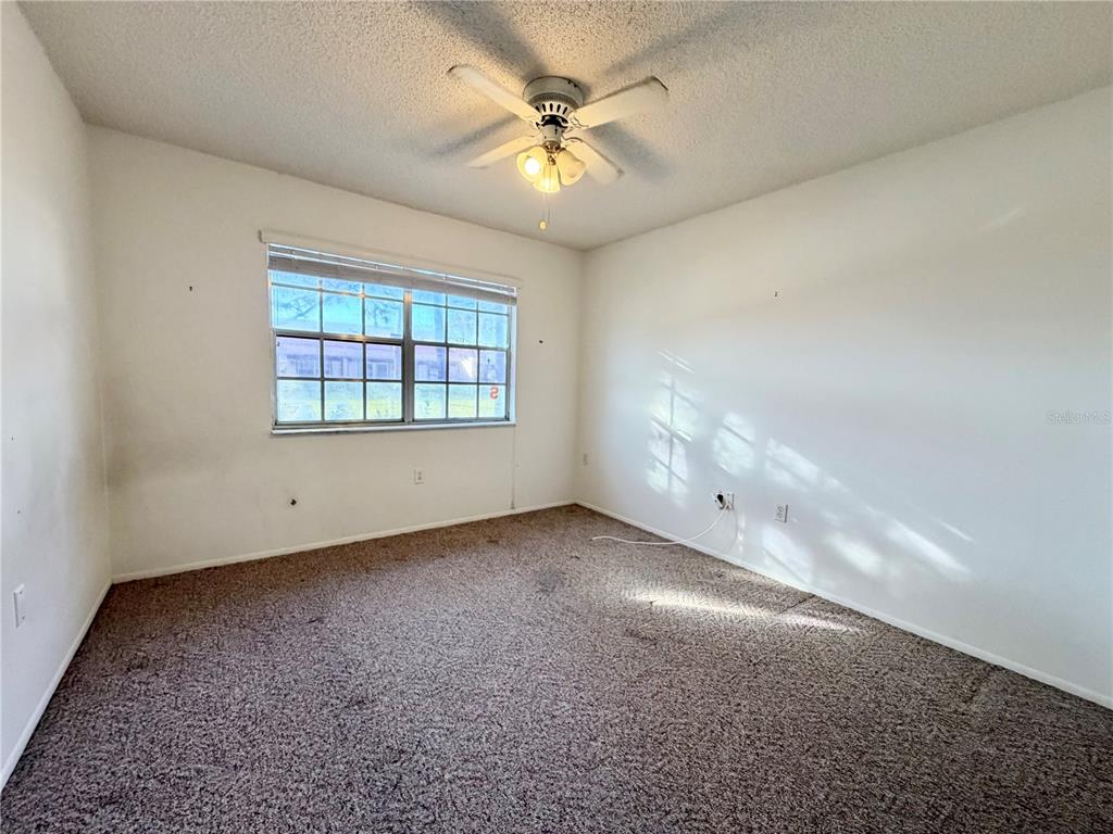 11210 Dollar Lake Drive, Unit 2 Port Richey, FL 34668 - Photo 10 of 15 an empty room with chandelier fan and windows