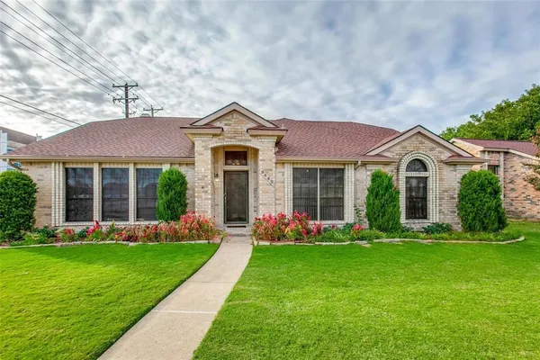 a front view of a house with a yard and trees