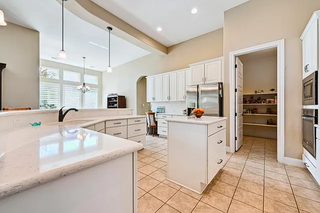 a kitchen with stainless steel appliances kitchen island granite countertop a stove a sink a dining table and chairs with wooden floor