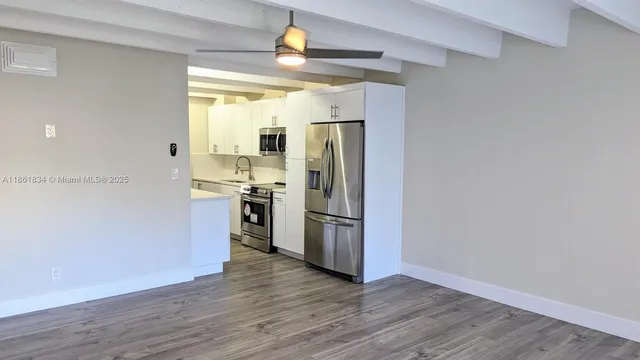 a kitchen with stainless steel appliances a refrigerator and a hard wood floor