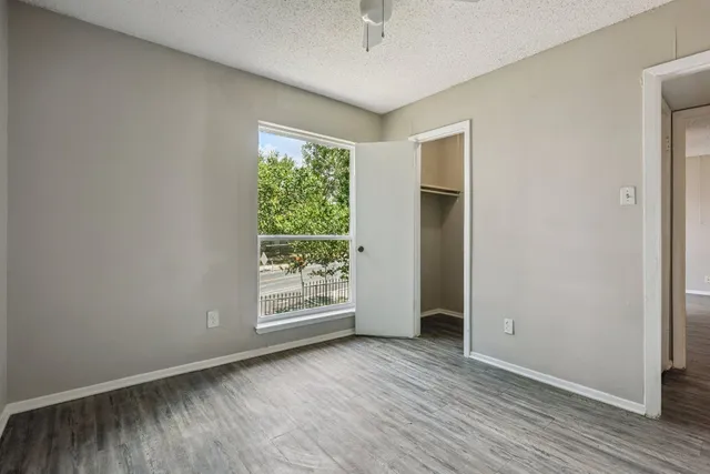 an empty room with wooden floor and windows