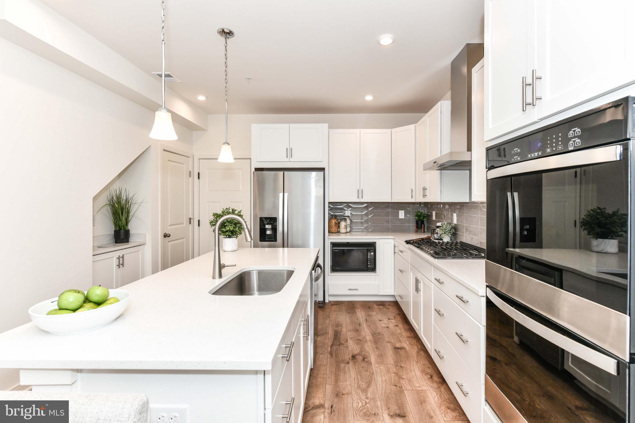 45922 Swallow Terrace Sterling, VA 20165 - Photo 11 of 36 a kitchen with stainless steel appliances kitchen island granite countertop a sink a stove and cabinets