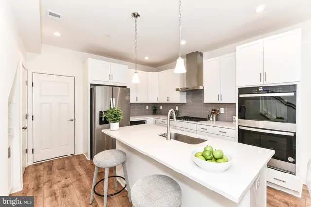 a kitchen with a refrigerator a stove a sink and white cabinets with wooden floor