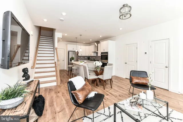 a kitchen with stainless steel appliances kitchen island granite countertop a dining table chairs and a refrigerator