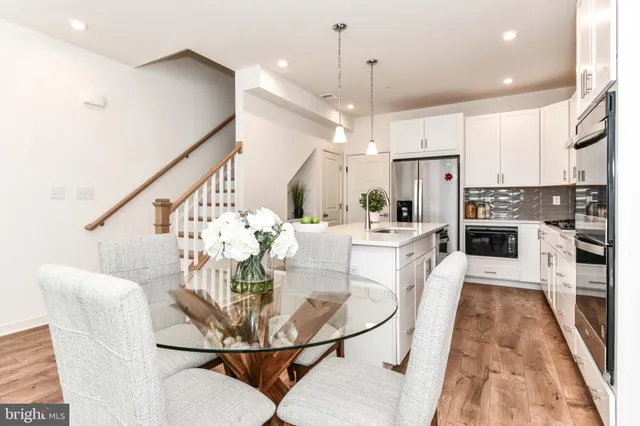 a kitchen with stainless steel appliances kitchen island granite countertop a dining table chairs and a view of living room