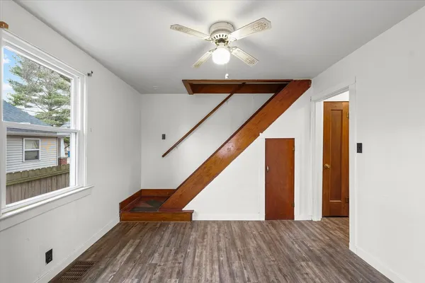 a view of empty room with wooden floor and fan