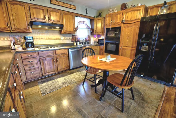 a kitchen with stainless steel appliances granite countertop table chairs and a refrigerator